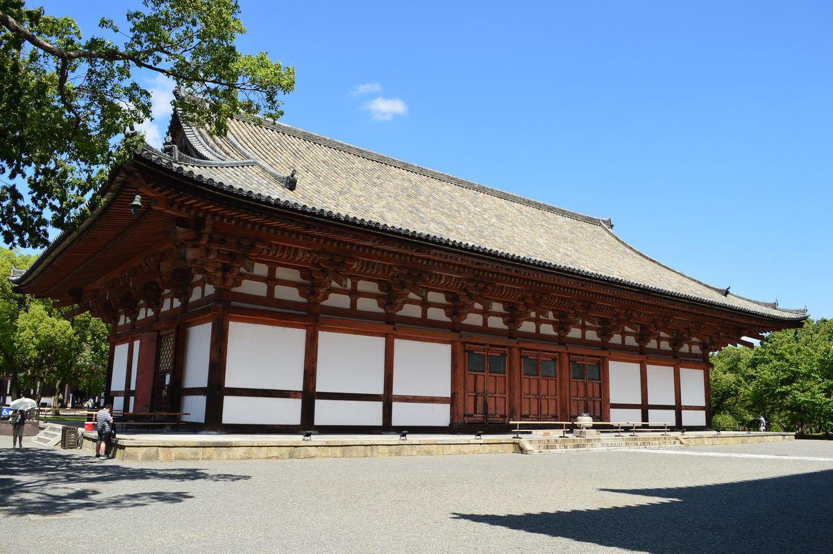 東寺講堂外觀:朱紅色柱子、白牆與單層瓦屋頂的長形佛堂,白天晴空