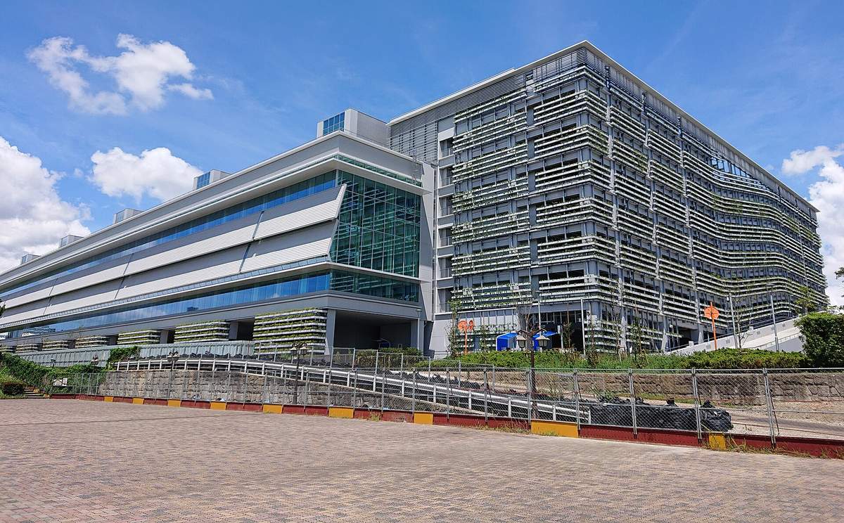 東京 Big Sight 南展示棟外觀:低矮的玻璃帶狀建築連著一棟外牆是橫向百葉的方形大樓,前面是空曠的磚鋪廣場,晴天