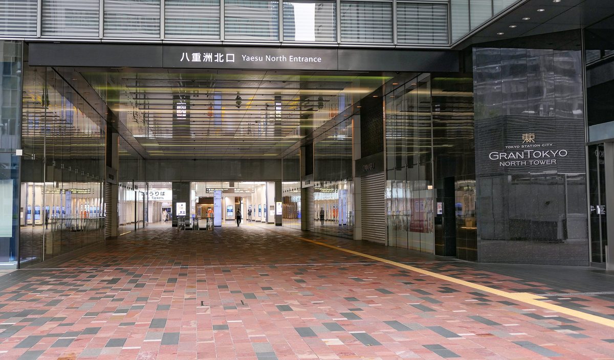 JR 東京站八重洲北口的站外入口:門楣上寫著八重洲北口 Yaesu North Entrance,紅褐色地磚的通道往裡通到售票處,右側黑色牆面寫著 GRANTOKYO NORTH TOWER