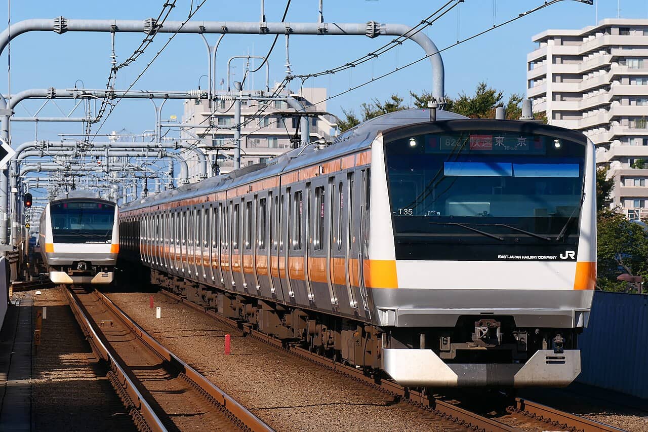 JR Chuo Rapid Line E233 series train in orange livery — the east-west trunk connecting Shinjuku and Tokyo Station