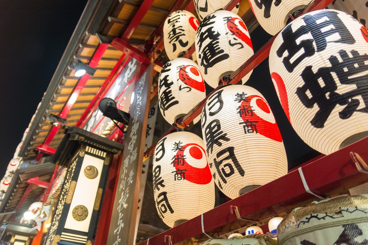 Rows of white paper lanterns marked in red, carrying the names of donor businesses, lighting the Asakusa Otori Shrine precinct at night
