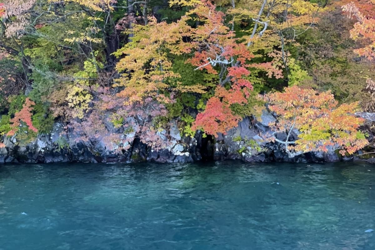 Lake Towada sightseeing cruise from Nenokuchi to Yasumiya, ringed by autumn foliage against deep blue caldera water