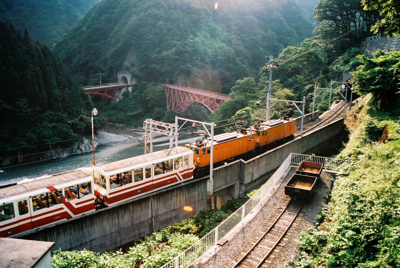 黑部峽谷側面敞開的開放式托盤車車廂行駛在溪谷邊