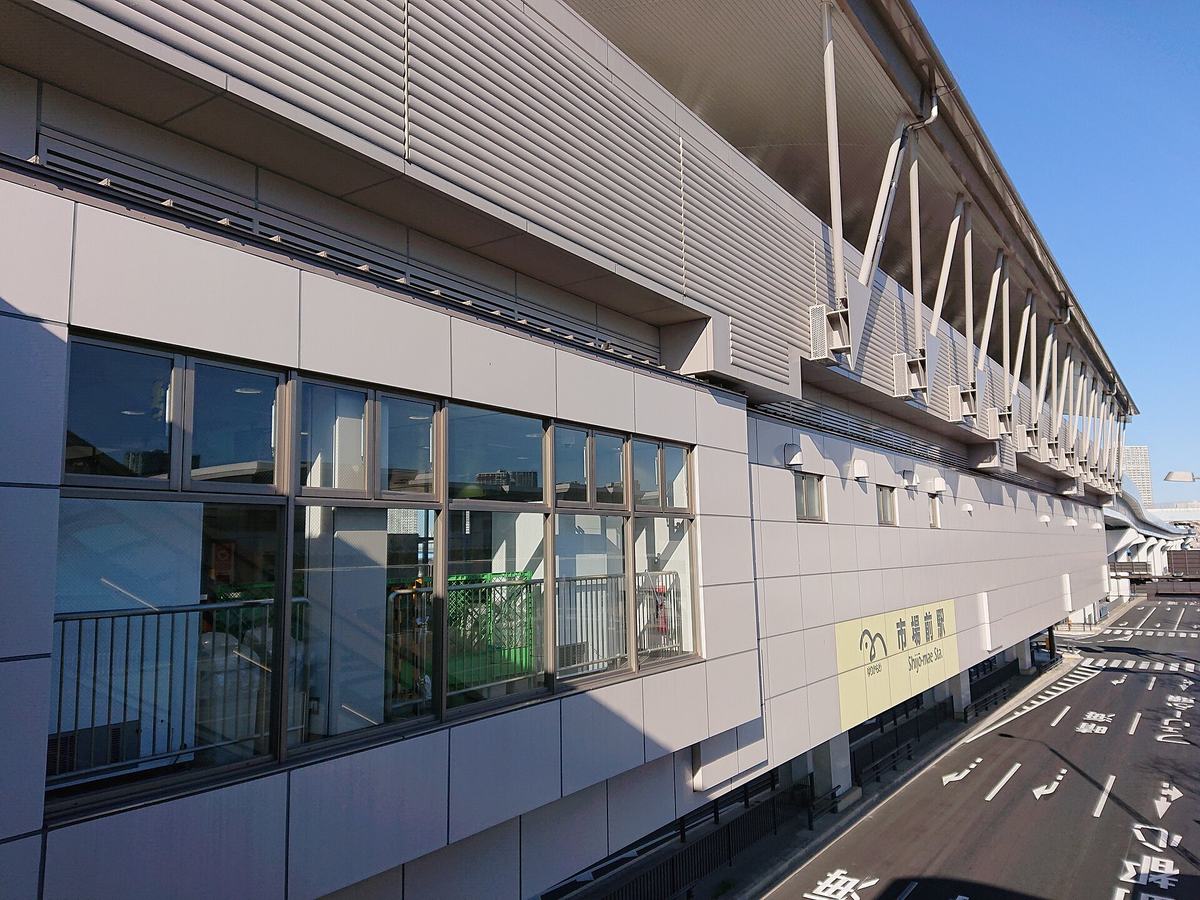 The elevated station building at Shijo-mae on the Yurikamome line, with the yellow Shijō-mae Sta. nameboard mounted on its flank above the road