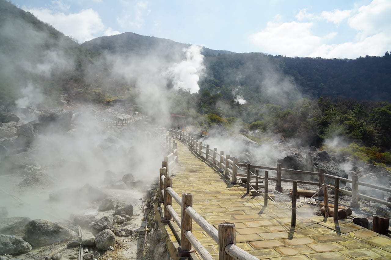 雲仙地獄噴著白色硫磺蒸氣的地熱原與木棧步道