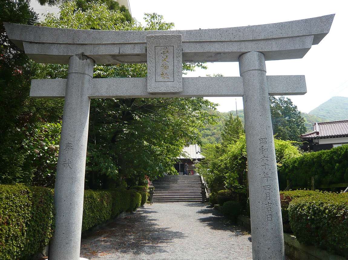 The stone torii of Unzen's Onsen Shrine with its carved nameplate and the stairway to the shrine hall behind
