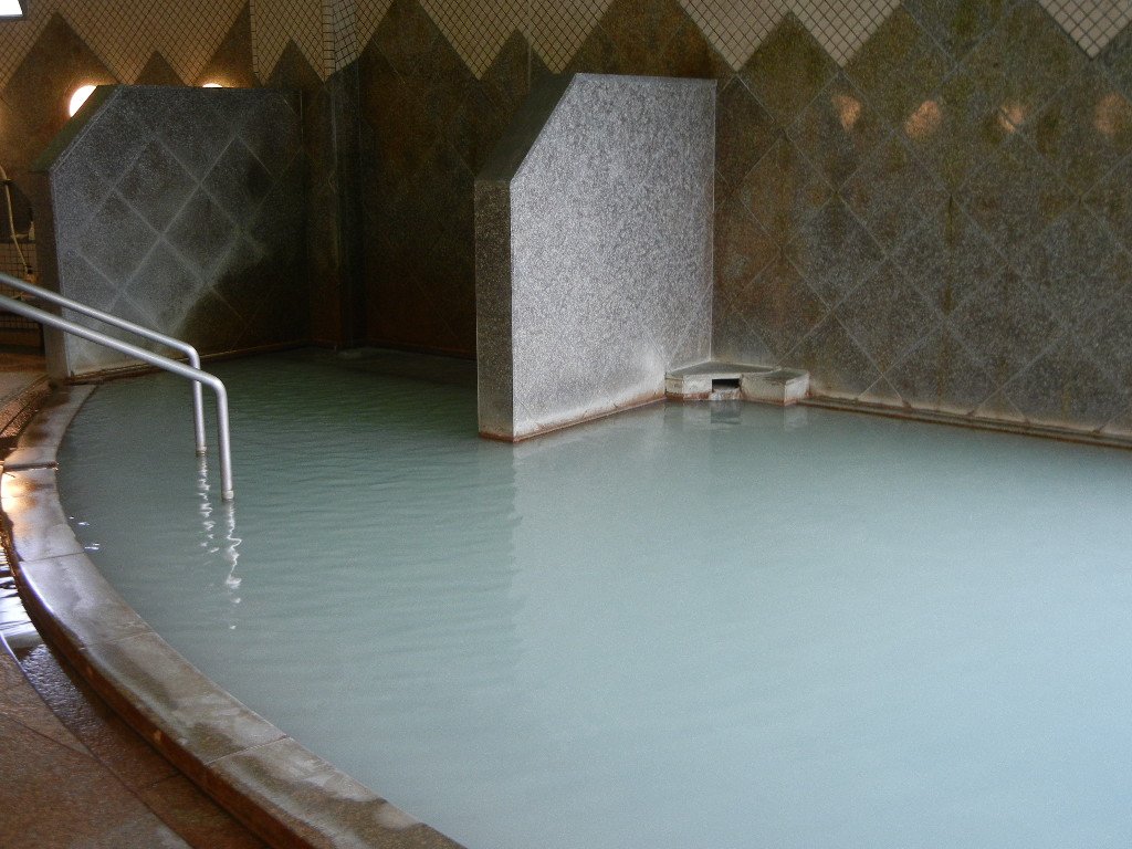 The milky-white sulfur bath at Unzen's Kojigoku Onsen-kan, cloudy spring water in a wooden bathhouse