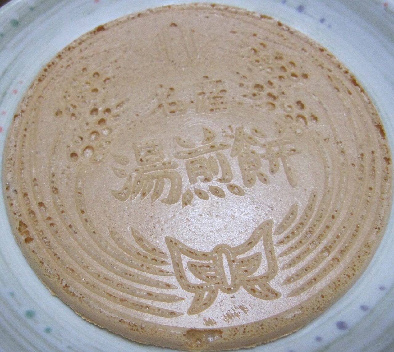 Close-up of a yu-senpei wafer stamped with the characters for 'yu-senpei' and a decorative pattern