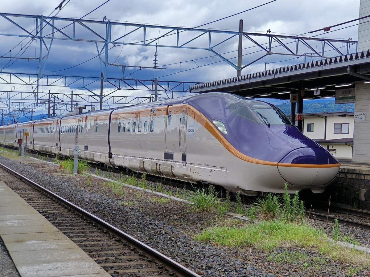 A Yamagata Shinkansen E8 series Tsubasa in purple-and-gold livery standing at a platform on the Yamagata Line