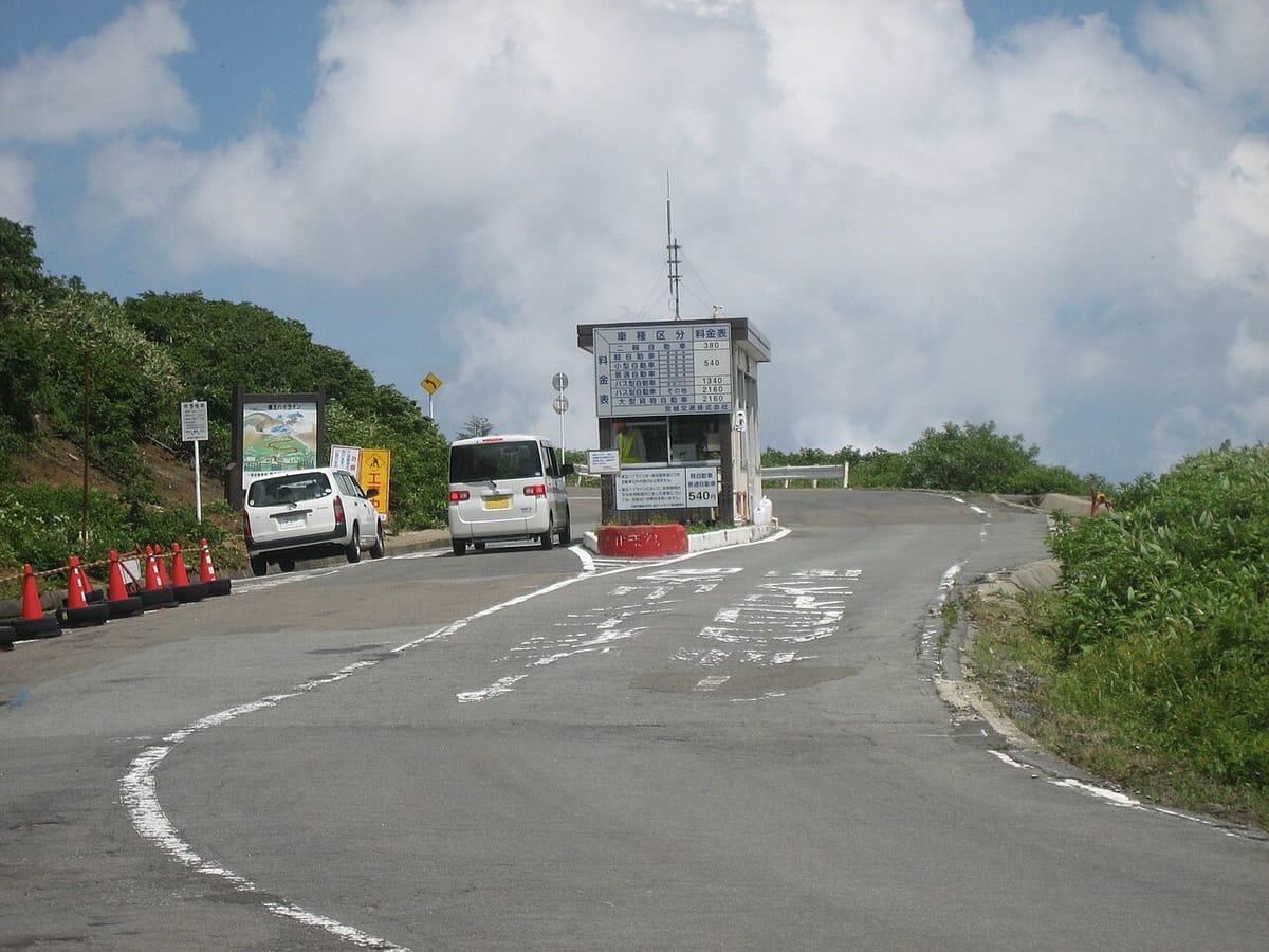 蔵王ハイライン料金所,車輛停在收費亭前,後方是通往刈田岳山頂的山路